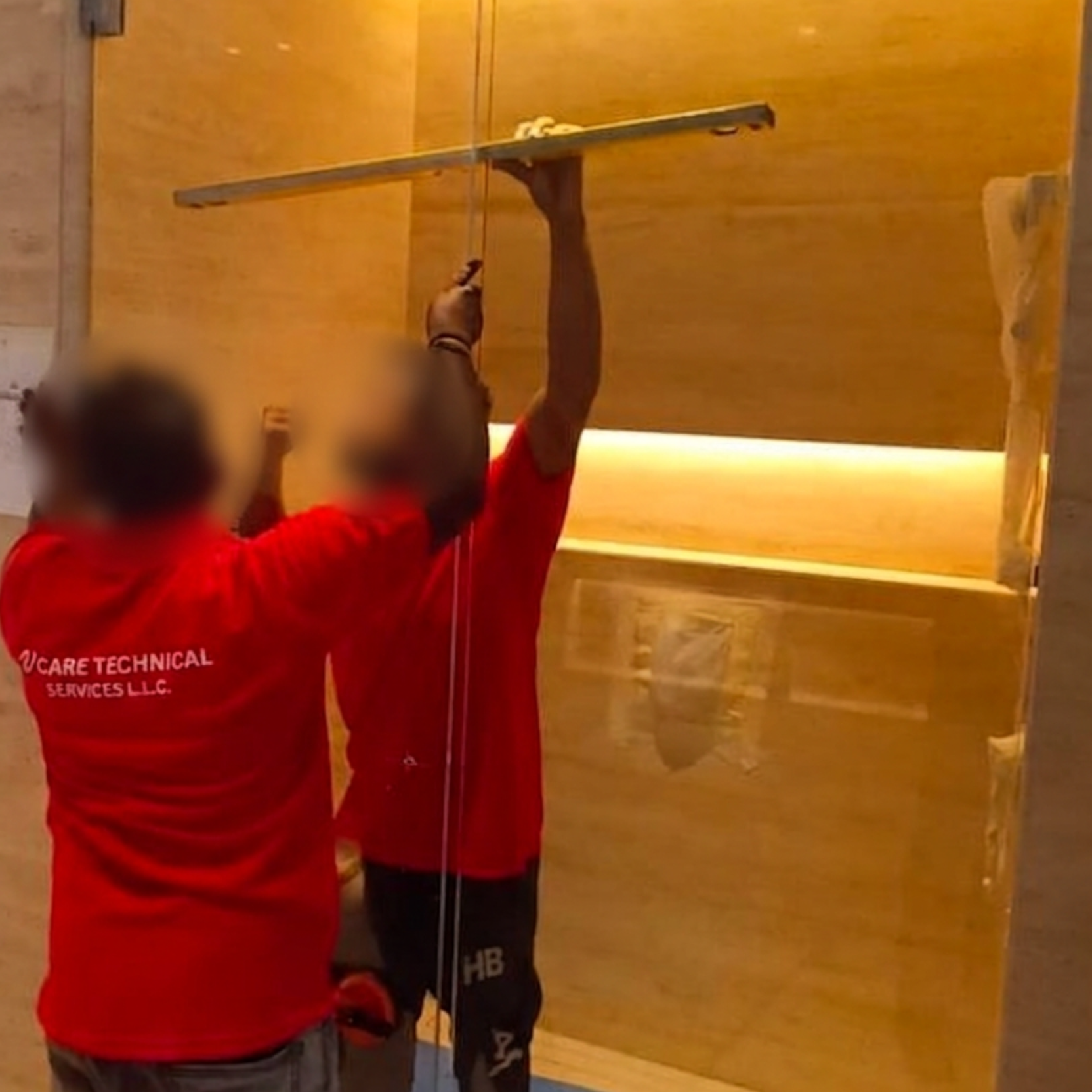 V CARE technicians in branded uniforms installing a glass partition on site in Dubai